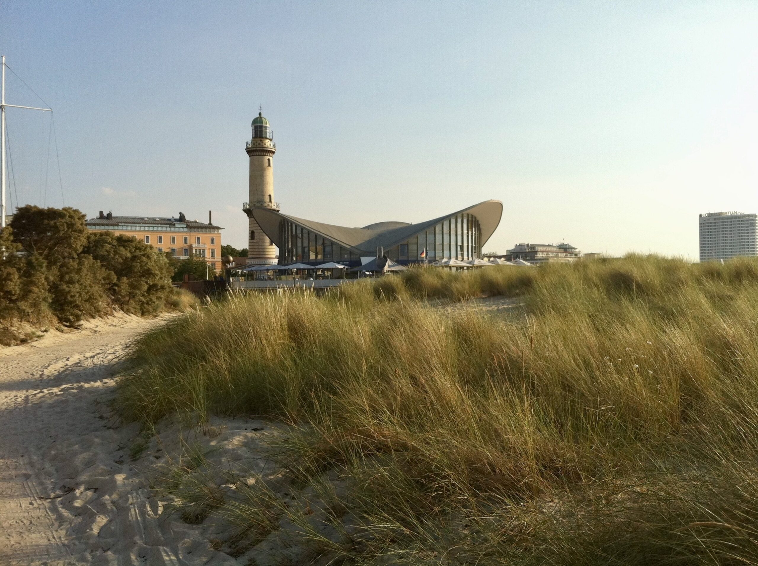 Leuchtturm Travemünde mit Gebäude hinter Düne, wichtig für die Verwaltung von Ferienimmobilien durch Favorent.