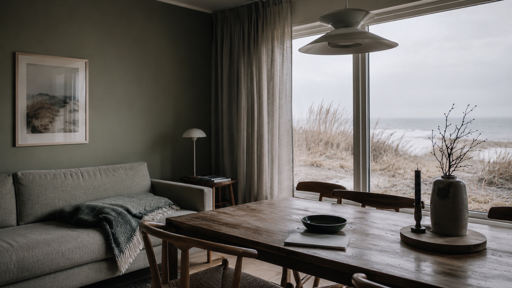 Wohnzimmerblick mit Holztisch, Sofa und Meerblick; Ferienhaus-Interieur für Urlaubsgäste.