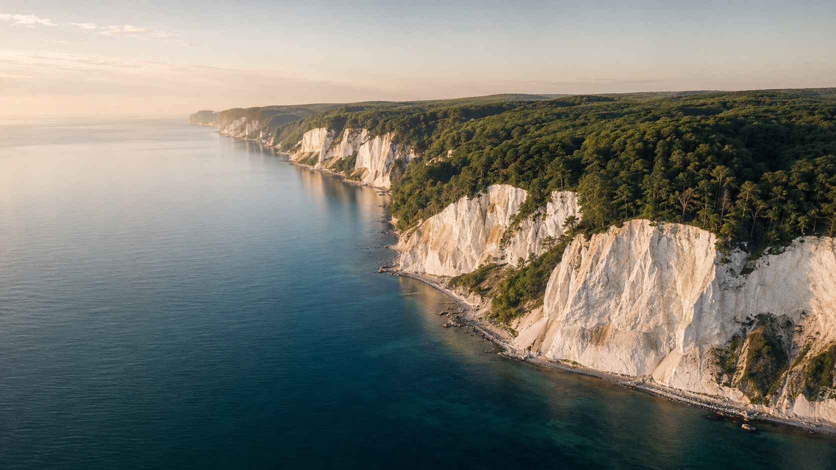 Kreidefelsenküste Rügen mit tiefblauem Meer und grünen Bäumen, beliebtes Ziel für Ferienhausurlaub.