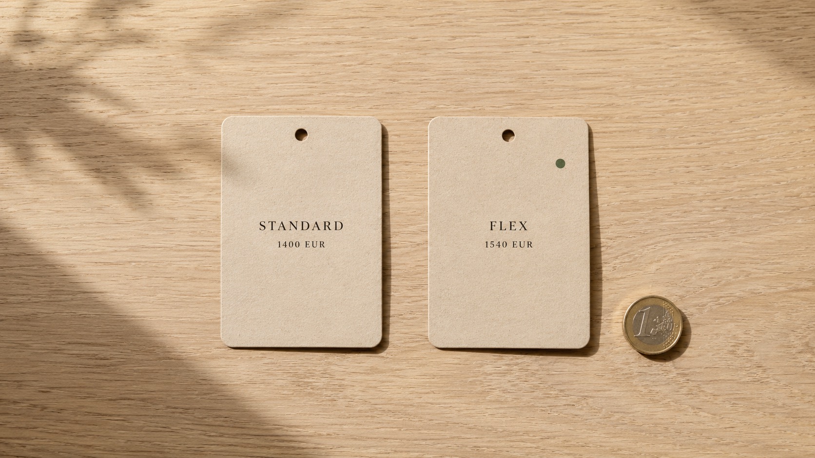 Zwei beige Kärtchen, 'Standard 1400 EUR' und 'Flex 1540 EUR', liegen neben einer Euro-Münze auf Holzgrund.